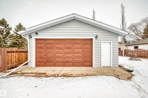 Detached garage with light grey siding, a brown panel garage door, and a white side door - 4312 43 Avenue, Leduc, AB - Outdoor With Exterior