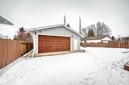 Detached garage with a brown panel door, light grey siding, and a white side door - 4312 43 Avenue, Leduc, AB - Outdoor With Exterior