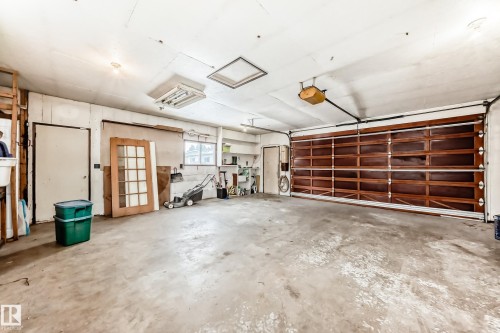Spacious garage featuring a concrete floor, a wooden garage door, and ample overhead lighting - 4312 43 Avenue, Leduc, AB - Indoor Photo Showing Garage