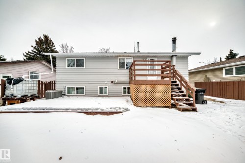 The property features a rear deck with wood railings and lattice skirting, accessed via stairs, overlooking a snow-covered yard - 4312 43 Avenue, Leduc, AB - Outdoor With Deck Patio Veranda With Exterior