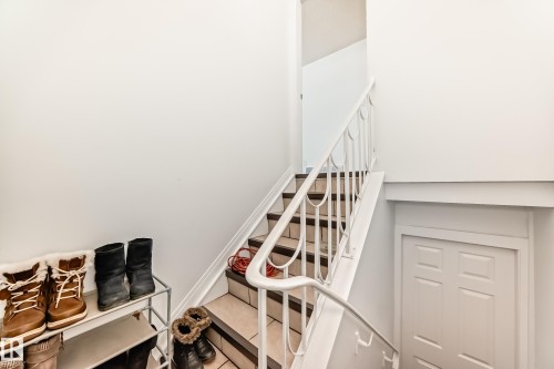 Interior staircase with white walls, a white banister, and tiled steps - 4312 43 Avenue, Leduc, AB - Indoor Photo Showing Other Room