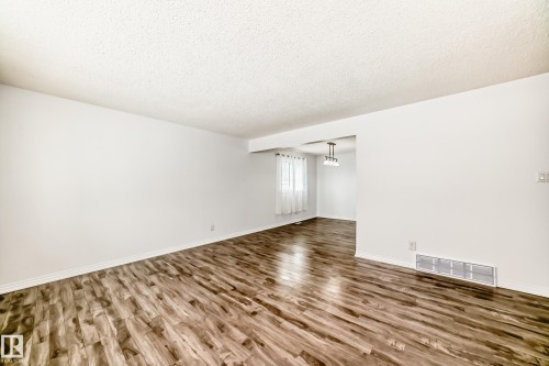 This living area features wood-look flooring and white walls, creating a bright and inviting atmosphere - 4312 43 Avenue, Leduc, AB - Indoor Photo Showing Other Room
