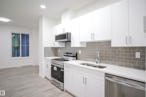 Kitchen with appliances with stainless steel finishes, white cabinetry, tasteful backsplash, light wood-style flooring, and recessed lighting - 53 7110 Keswick Common Sw, Edmonton, AB - Indoor Photo Showing Kitchen With Double Sink With Upgraded Kitchen