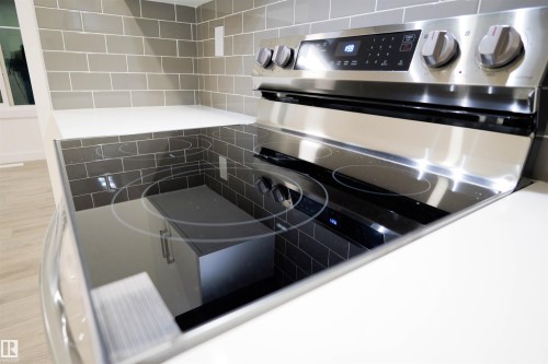 Kitchen view of stainless steel electric range oven and tile walls - 53 7110 Keswick Common Sw, Edmonton, AB - Indoor Photo Showing Kitchen