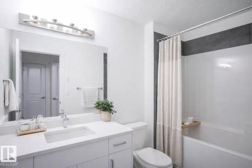 Virtually Staged Full bathroom with shower / bathtub combination with curtain, vanity, and a textured ceiling - 53 7110 Keswick Common Sw, Edmonton, AB - Indoor Photo Showing Bathroom