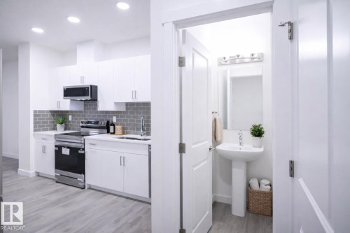 Virtually Staged Kitchen with stainless steel appliances, white cabinetry, light wood-type flooring, backsplash, and recessed lighting - 53 7110 Keswick Common Sw, Edmonton, AB - Indoor Photo Showing Kitchen