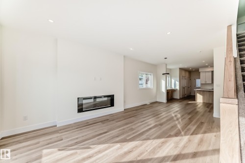 Open concept living area featuring light-toned flooring, recessed lighting, and a modern wall-mounted fireplace - 10718 149 Street Nw, Edmonton, AB - Indoor Photo Showing Living Room With Fireplace