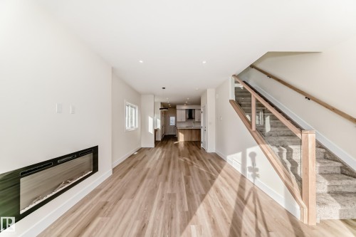 This open concept living area features light-toned flooring, a sleek fireplace, and recessed lighting - 10718 149 Street Nw, Edmonton, AB - Indoor Photo Showing Other Room With Fireplace