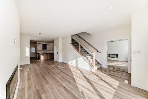 Bright open concept living area featuring light-toned flooring, recessed lighting, and a modern kitchen visible in the background - 10718 149 Street Nw, Edmonton, AB - Indoor