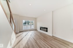 Living area featuring light-toned flooring, recessed lighting, and a modern wall-mounted fireplace - 