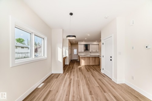 The property features plank flooring and a modern light fixture, with a window providing exterior views - 10718 149 Street Nw, Edmonton, AB - Indoor Photo Showing Other Room