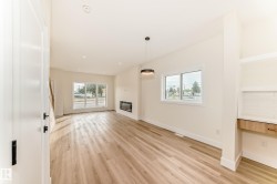 This bright living area features light wood flooring, a modern fireplace, and large windows that provide abundant natural light - 