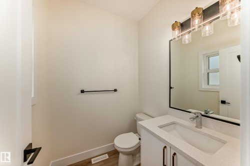 This powder room features a white vanity with a rectangular sink, a chrome faucet, and a large mirror with a black frame - 10718 149 Street Nw, Edmonton, AB - Indoor Photo Showing Bathroom