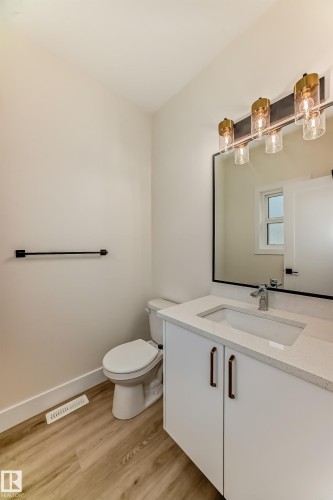 The bathroom features wood-look flooring, a white vanity with a light-colored countertop, and a vanity light fixture with four lights - 10718 149 Street Nw, Edmonton, AB - Indoor Photo Showing Bathroom