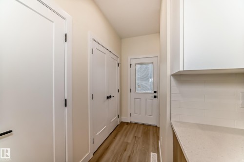 This area features light-colored walls, white doors with dark hardware, and a light wood-look floor - 10718 149 Street Nw, Edmonton, AB - Indoor Photo Showing Other Room