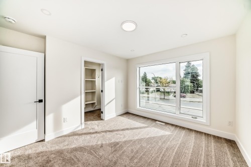 Room with neutral-toned carpet, a large window, and an open closet with shelving - 10718 149 Street Nw, Edmonton, AB - Indoor Photo Showing Other Room