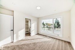 Room with neutral-toned carpet, a large window, and an open closet with shelving - 