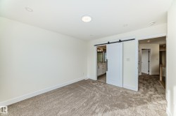 Carpeted room with recessed lighting and a white barn door - 
