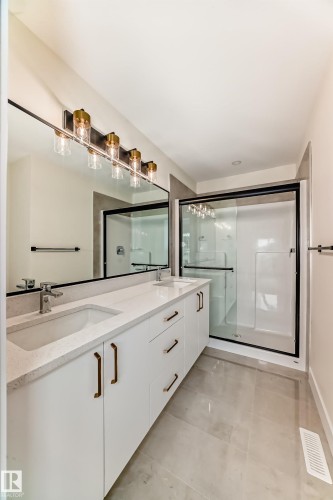 Bathroom featuring a double vanity with light-colored countertops, undermount sinks, and white cabinetry with brass-toned hardware - 10718 149 Street Nw, Edmonton, AB - Indoor Photo Showing Bathroom