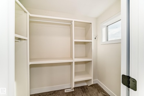 Closet with built-in shelving, hanging rods, and a window for natural light - 10718 149 Street Nw, Edmonton, AB - Indoor With Storage