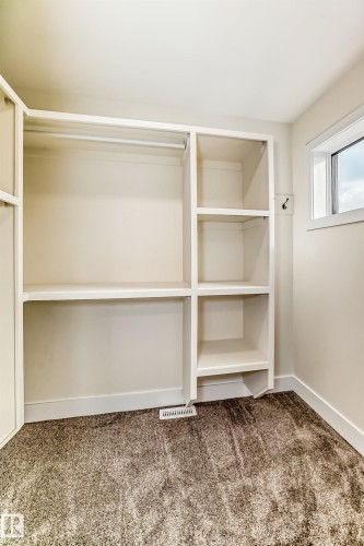 This space features built-in shelving, a clothes hanging rod, and carpeted flooring - 10718 149 Street Nw, Edmonton, AB - Indoor With Storage