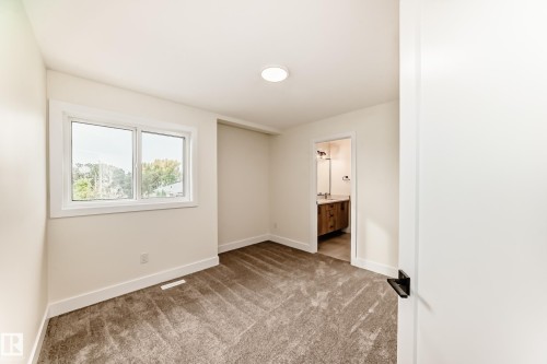 This room features carpeted flooring, a window with views of trees, and a modern ceiling light fixture - 10718 149 Street Nw, Edmonton, AB - Indoor Photo Showing Other Room