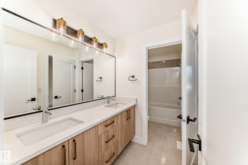 Bathroom featuring a spacious double vanity with two sinks, a large mirror, and modern light fixtures - 10718 149 Street Nw, Edmonton, AB - Indoor Photo Showing Bathroom