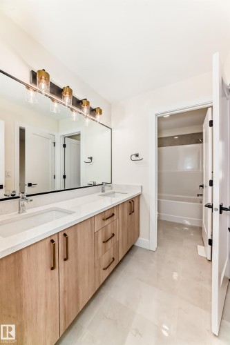 Bathroom featuring a double vanity with light wood cabinetry, white countertops, and a large mirror - 10718 149 Street Nw, Edmonton, AB - Indoor Photo Showing Bathroom