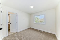 This room features plush grey carpeting, white walls, and a window providing natural light - 