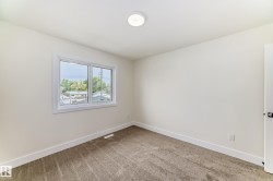 This room features light-colored walls, a window providing a view of surrounding structures and trees, and a ceiling light fixture - 