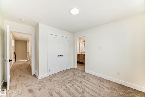 This room features neutral-toned carpet flooring and white walls, complemented by white trim and doors - 10718 149 Street Nw, Edmonton, AB - Indoor Photo Showing Other Room