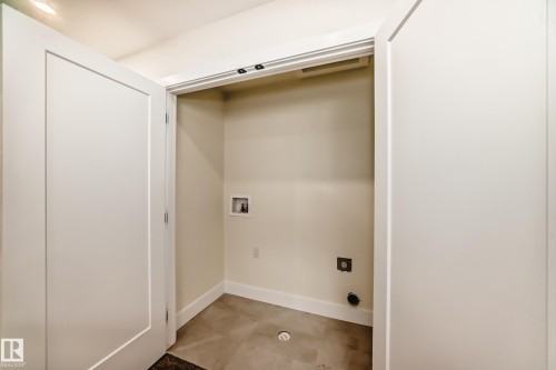 This dedicated laundry space features tile flooring, white baseboards, and a recessed light for illumination - 10718 149 Street Nw, Edmonton, AB - Indoor Photo Showing Other Room