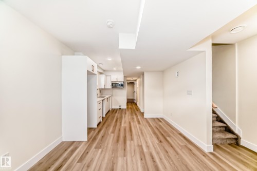 This bright open-concept space features light-toned wood flooring, white walls, and recessed lighting - 10718 149 Street Nw, Edmonton, AB - Indoor Photo Showing Other Room