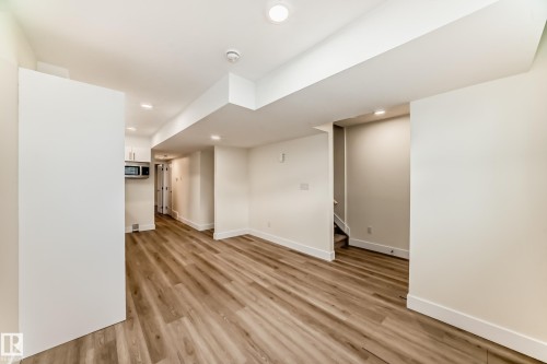 This open-concept room features light-toned wood flooring, recessed lighting, and white walls - 10718 149 Street Nw, Edmonton, AB - Indoor Photo Showing Other Room