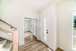 Entryway featuring hardwood floors, a white door with a vertical window, and a mirrored closet - 