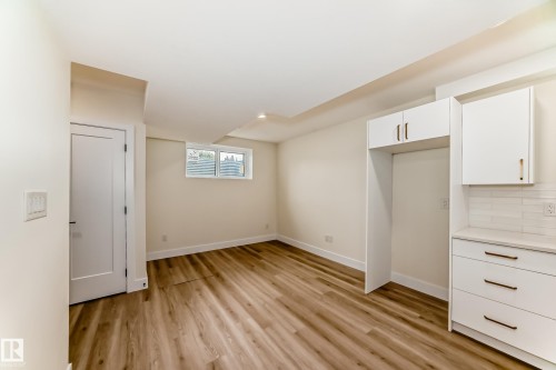 This space features light wood-look flooring, light-colored walls, and a window with horizontal blinds - 10718 149 Street Nw, Edmonton, AB - Indoor Photo Showing Other Room