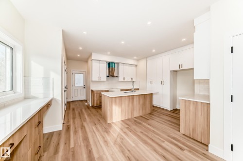 The property features a bright kitchen with light wood-style flooring, white countertops, and white and light wood cabinetry - 10718 149 Street Nw, Edmonton, AB - Indoor Photo Showing Kitchen