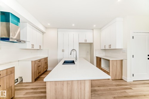The kitchen features white upper cabinetry, wood-toned lower cabinetry, and light countertops - 10718 149 Street Nw, Edmonton, AB - Indoor Photo Showing Other Room