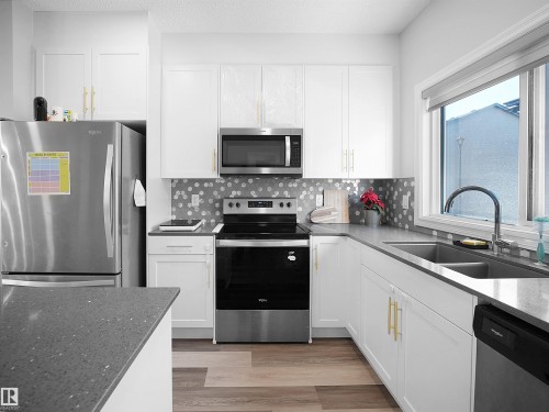 The kitchen features white cabinetry, stainless steel appliances, a double basin sink, and a modern tiled backsplash - 138 804 Welsh Drive, Edmonton, AB - Indoor Photo Showing Kitchen With Double Sink