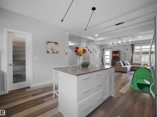 The property features an open-concept living area with multi-toned flooring and a kitchen island with storage and a light-colored countertop - 138 804 Welsh Drive, Edmonton, AB - Indoor