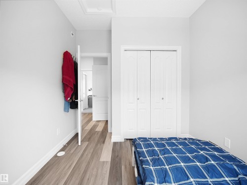 The property features light-colored walls, wood-style flooring, white bi-fold doors, and a ceiling hatch - 138 804 Welsh Drive, Edmonton, AB - Indoor Photo Showing Bedroom