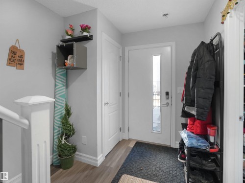 The entrance features a white door with a vertical window, light grey walls, and wood-style flooring - 138 804 Welsh Drive, Edmonton, AB - Indoor