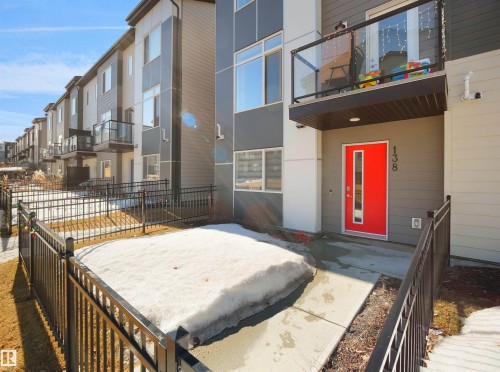 This property features a contemporary exterior with a bold red front door and a private balcony with a glass railing - 138 804 Welsh Drive, Edmonton, AB - Outdoor