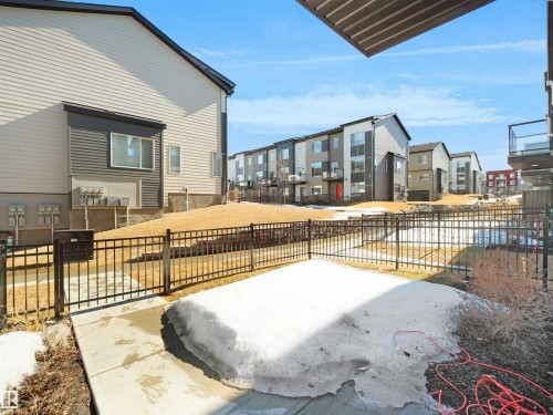 The property features a private patio area and a black metal fence, with a view of other residential buildings in the background - 138 804 Welsh Drive, Edmonton, AB - Outdoor With Exterior