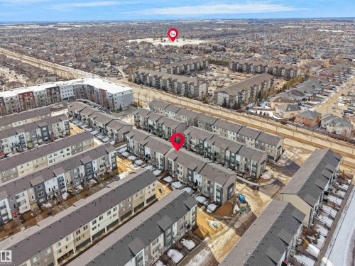 Aerial view of the property and surrounding residential neighborhood, featuring rows of townhomes and apartment buildings under a clear sky - 138 804 Welsh Drive, Edmonton, AB - Outdoor With View