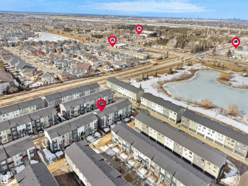This aerial view showcases the property within a community featuring numerous residential structures and a frozen pond - 138 804 Welsh Drive, Edmonton, AB - Outdoor With View