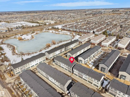 Aerial view showcasing the property within a community of townhomes and its proximity to a pond - 138 804 Welsh Drive, Edmonton, AB - Outdoor With View