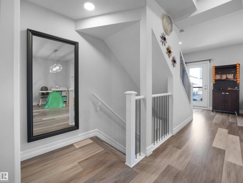 The property features light wood flooring, light grey walls, and a staircase with white railings and dark balusters - 138 804 Welsh Drive, Edmonton, AB - Indoor Photo Showing Other Room