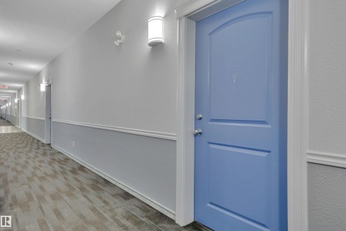 The property features a private entrance with a distinctive blue door and chrome hardware, framed by white trim - 108 1204 156 Street, Edmonton, AB - Indoor Photo Showing Other Room