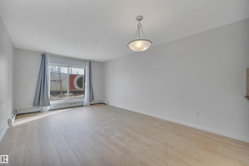 The property features light-colored flooring, a large window, and a ceiling-mounted light fixture - 108 1204 156 Street, Edmonton, AB - Indoor Photo Showing Other Room